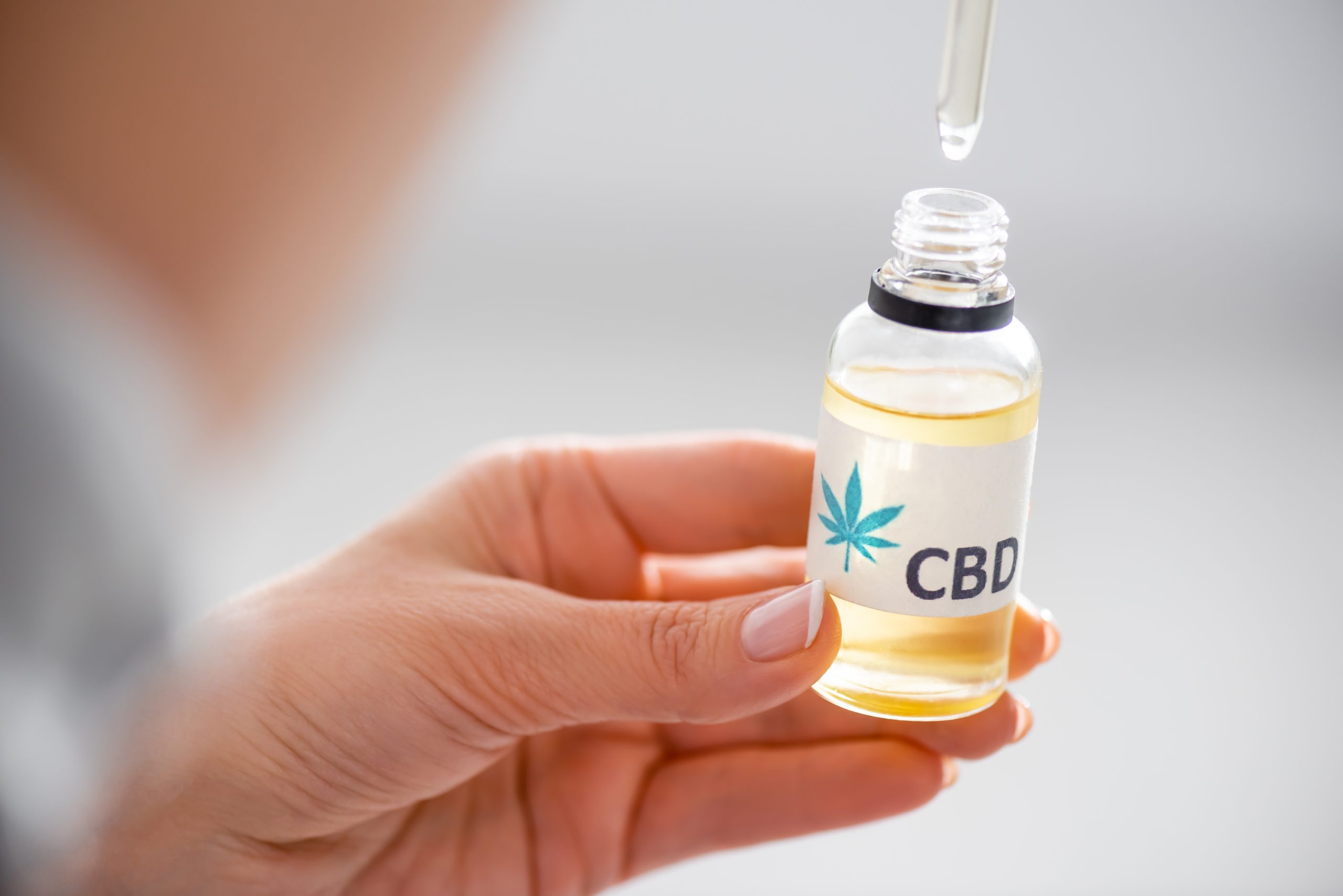 selective focus of woman holding pipette and bottle with cbd lettering